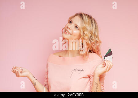 Giovane studente hipster donna con capelli colorati e tatuaggio tenendo le carte di credito. Concetto di acquisti Foto Stock