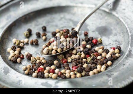 Grani di pepe misto a cucchiaio Foto Stock