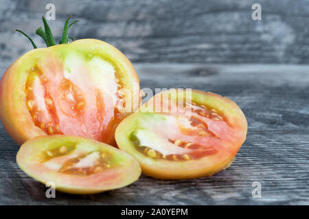 Grande giallo fresco tagliato il pomodoro isolato su uno sfondo di legno. Foto Stock