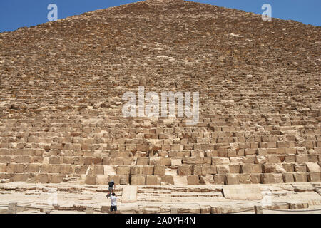 Due turisti preparando a fare foto a lato occidentale della piramide di Khufu o la piramide di Cheop, la più antica e la più grande delle tre piramidi nel Foto Stock