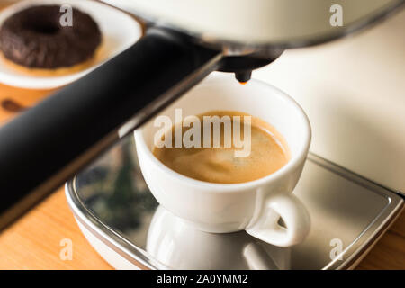 Macchina per caffè espresso e tazza bianca con appena infuso di caffè espresso Foto Stock