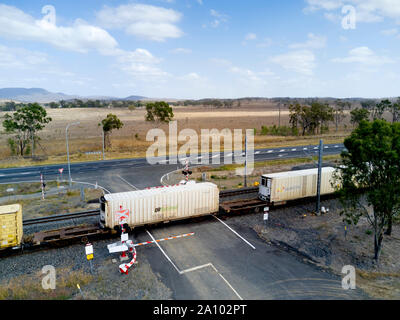 Antenna di trasporto misto treno passa attraverso un braccio controllato passaggio a livello voce lungo il lato dell'Autostrada di Bruce Queensland Australia Foto Stock