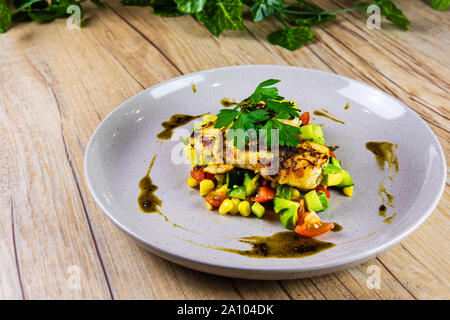 Pesce alla griglia su un letto di Salsa su una lastra grigia Foto Stock