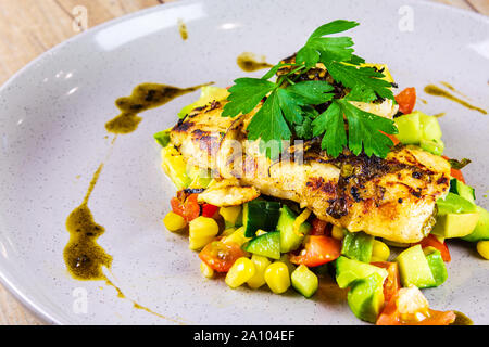 Pesce alla griglia su un letto di Salsa su una lastra grigia Foto Stock