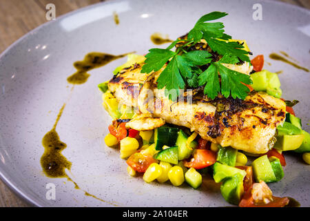 Pesce alla griglia su un letto di Salsa su una lastra grigia Foto Stock