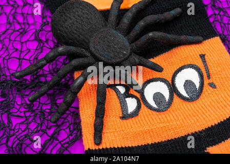 Il Ragno Nero e nero rigato e orange divertenti calzini sul luminoso sfondo viola. Boo! Vacanza Halloween celebrazione del concetto. Foto Stock