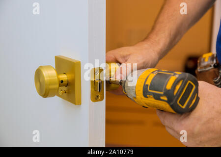 Installazione con un blocco nel battente della porta mediante un trapano cacciavite,per trattenere le viti, close-up. Foto Stock