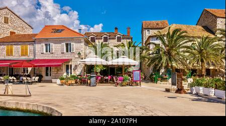 Un variopinto panorama di una località mediterranea in estate, con i ristoranti e le caffetterie lungo la passeggiata lungomare. Stari Grad, Isola di Hvar, Croazia. Foto Stock