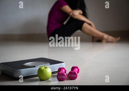 Close up bilancia nella parte anteriore di turbare la donna con nastro di misurazione, rosa dumbbell e mela verde. Uno stile di vita sano, cibo e sport concept. Foto Stock