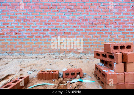 In mattoni e malta di sfondo a parete con detriti di costruzione in primo piano, spazio di copia Foto Stock