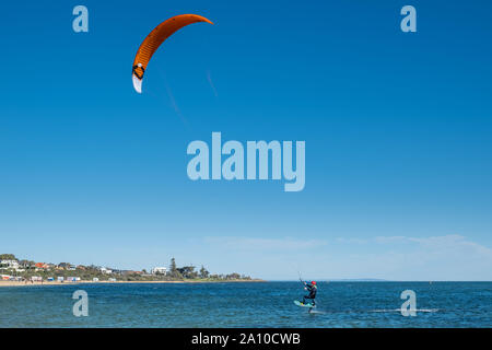 MELBOURNE, Australia - 31 August, 2019: Kite surfer si innalza al di sopra dell'acqua essendo tirato da vela Foto Stock