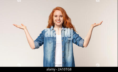 Gentile redhead girl diffondendo le mani, accogliente o il messaggio di saluto qualcuno Foto Stock