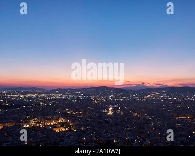 Panorama della città al tramonto. Crepuscolo paesaggio con la città, le montagne e le nuvole sotto i raggi del sole al tramonto. Atene, Grecia. Foto Stock