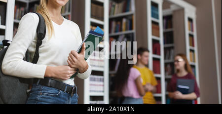 Ragazza giovane azienda libri sullo sfondo della libreria Foto Stock