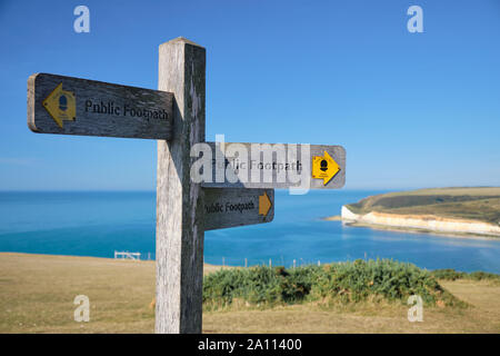 A tre vie sentiero pubblico le frecce di direzione sulla costa sud dell'Inghilterra, parte di South Downs. Rupi costiere e mare sfocata in background Foto Stock