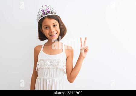 Bella ragazza bambino indossando princess crown in piedi isolato su sfondo bianco sorridente con la faccia felice occhiolino presso la telecamera facendo segno di vittoria. Foto Stock