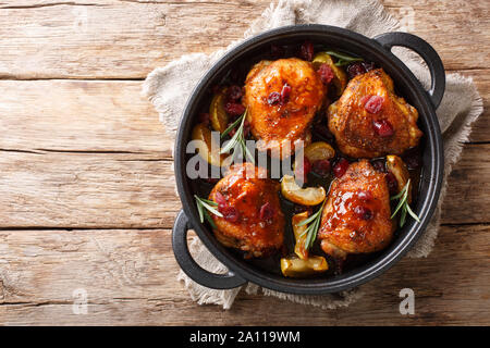 Croccante al forno fragranti cosce di pollo con mele, mirtilli e rosmarino closeup in una padella sul tavolo. parte superiore orizzontale vista da sopra Foto Stock