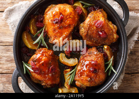 Stile rustico al forno cosce di pollo con mele, mirtilli e rosmarino close-up in una padella sul tavolo. Parte superiore orizzontale vista da sopra Foto Stock