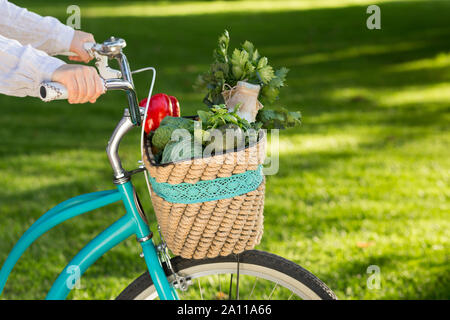 La donna a cavallo su moto con fresche verdure di fattoria Foto Stock