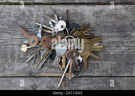 Un mazzo di vecchie chiavi differenti su uno sfondo di schede, vista dall'alto. Foto Stock