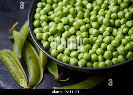 Crudo fresco verde biologico Piselli (Pisum sativum) nel recipiente Foto Stock