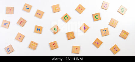 Alfabeto sparse lettere dei blocchi di legno piastrelle bianco su sfondo tabella. Vista superiore Foto Stock