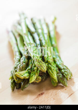 Mazzetto di punte di asparagi su una superficie in legno Foto Stock