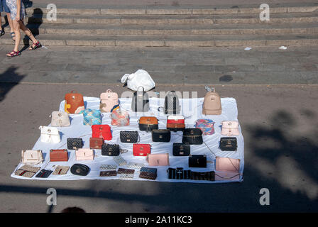 Illegale Street Traders Display del Fake Designer merci sul foglio bianco di Placa de Catalunya Barcellona Catalonia Spagna marciapiede offrendo Gucci Michael Kors Foto Stock