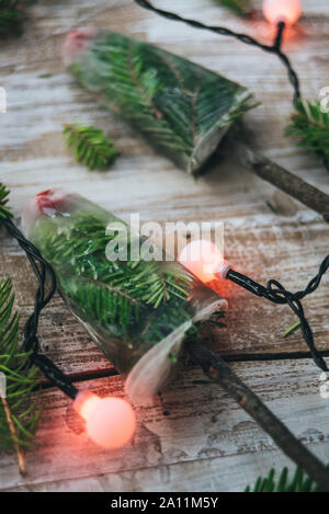 Due gelati su un bastone di rami di pino su tavola di legno con le luci di Natale Foto Stock