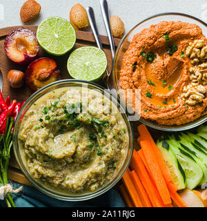 Veggie serving table con spuntini con verdure, frutti, baba ganoush e dip o diffusione di arrosto di peperone rosso e dadi. sano cibo vegan per celebr Foto Stock