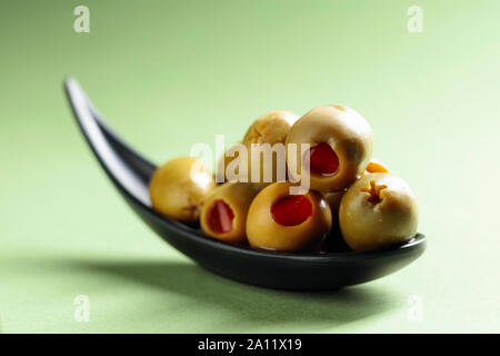 Stuzzicanti Olive farcite con peperoncino rosso in nero piccolo recipiente. Foto Stock