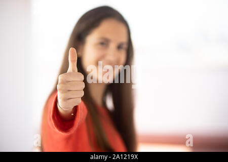 Chica adolescente desenfocada mostrando el pulgar hacia arriba Foto Stock
