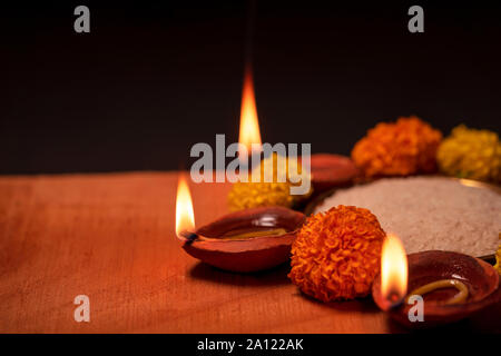 Felice Diwali che intendono con argilla diya o olio lampada decorata tradizionalmente con i fiori e il riso in una ciotola. Concetto di sfondo per il Diwali con spazio di copia Foto Stock