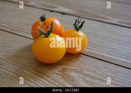 Gruppo di mini pomodori ciliegini gialli su un rustico tavolo in legno Foto Stock