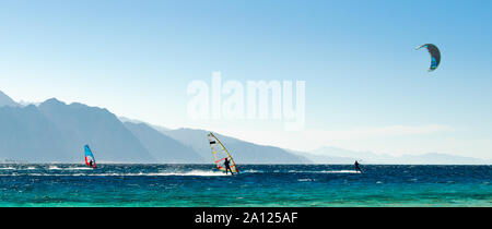 Surfisti e kitesurfisti ride in Mar Rosso sullo sfondo della costa rocciosa in Egitto Dahab Foto Stock