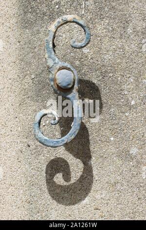 Dipinto di blu vecchia porta di metallo o il fermo del finestrino nel sole brillante contro una parete testurizzata.La cattura è curvo e proietta un ombra sul muro. Foto Stock