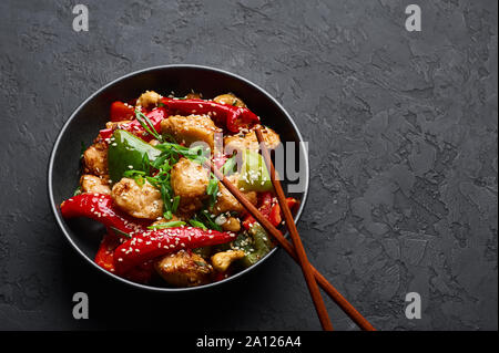 Pollo di Schezwan o Dragon pollo in vaso nero in ardesia scuro dello sfondo. Il Szechuan Pollo è popolare indo-cinese piatto piccante con peperoncino, ch Foto Stock