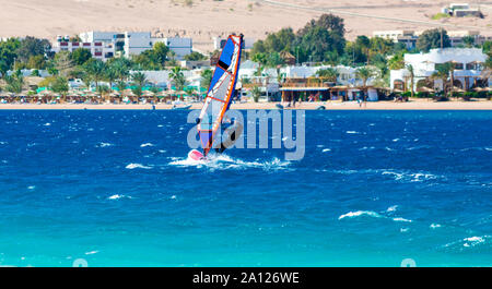 Windsurf scorre sullo sfondo della spiaggia con un hotel e le palme in Egitto Dahab Foto Stock