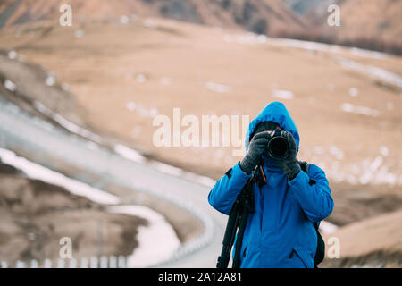 Giovane adulto uomo caucasico turistica viaggiatore Backpacker fotografo a scattare foto foto nel bellissimo paesaggio delle montagne all'inizio dell'inverno. Foto Stock