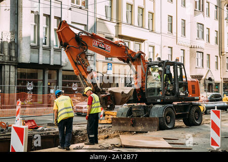 Riga, Lettonia - 9 Giugno 2019: i lavoratori sono impegnati nella riparazione di comunicazioni sulla Aleksandra Caka street con un escavatore. Foto Stock