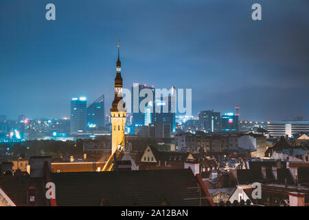 Tallinn, Estonia - 2 Luglio 2, 2019: Torre del Municipio sullo sfondo con moderni grattacieli urbani. Notte Centro Città Architettura. Foto Stock