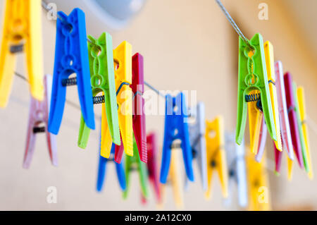 Clothespins colorate sulle staffe. In plastica linea clothespins in diversi colori su blur sullo sfondo Foto Stock