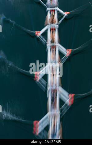 Moto sfocata vista aerea di un equipaggio a remi in barca sculling sull'acqua, metà corsa Foto Stock