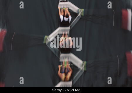 Moto sfocata vista aerea di un equipaggio a remi in barca sculling sull'acqua, metà corsa Foto Stock