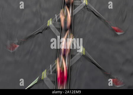 Moto sfocata vista aerea di un equipaggio a remi in barca sculling sull'acqua, metà corsa Foto Stock