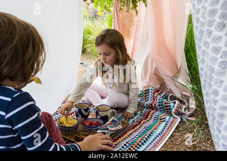 Ragazzo e ragazza che gioca in outdoor tenda improvvisata Foto Stock