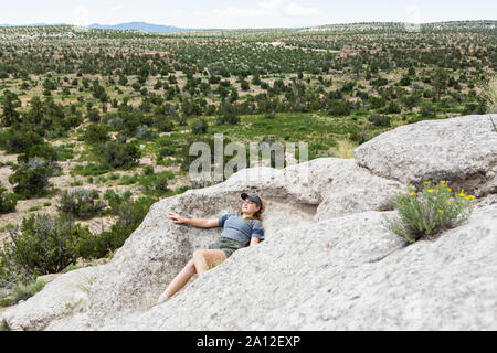 13 year old girl sdraiato sulla formazione di roccia, Tsankawi rovine, NM Foto Stock