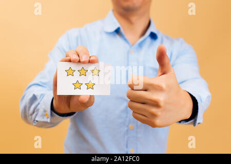 Imprenditore che mostra cinque stelle gialle card e pollice in alto di colore luminoso dello sfondo. Recensione, rating, classifica e il concetto di valutazione Foto Stock