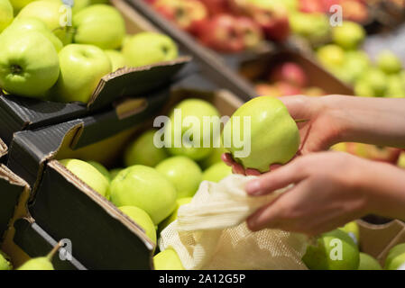 La donna decide di mele verdi al mercato degli agricoltori. Rifiuti Zero, plastica libera concetto. Uno stile di vita sostenibile. Cotone riutilizzabili e maglia eco borse per lo shopping Foto Stock