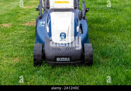 In prossimità della parte anteriore di una lancia e Jackson tosaerba elettrico su un giardino prato Foto Stock